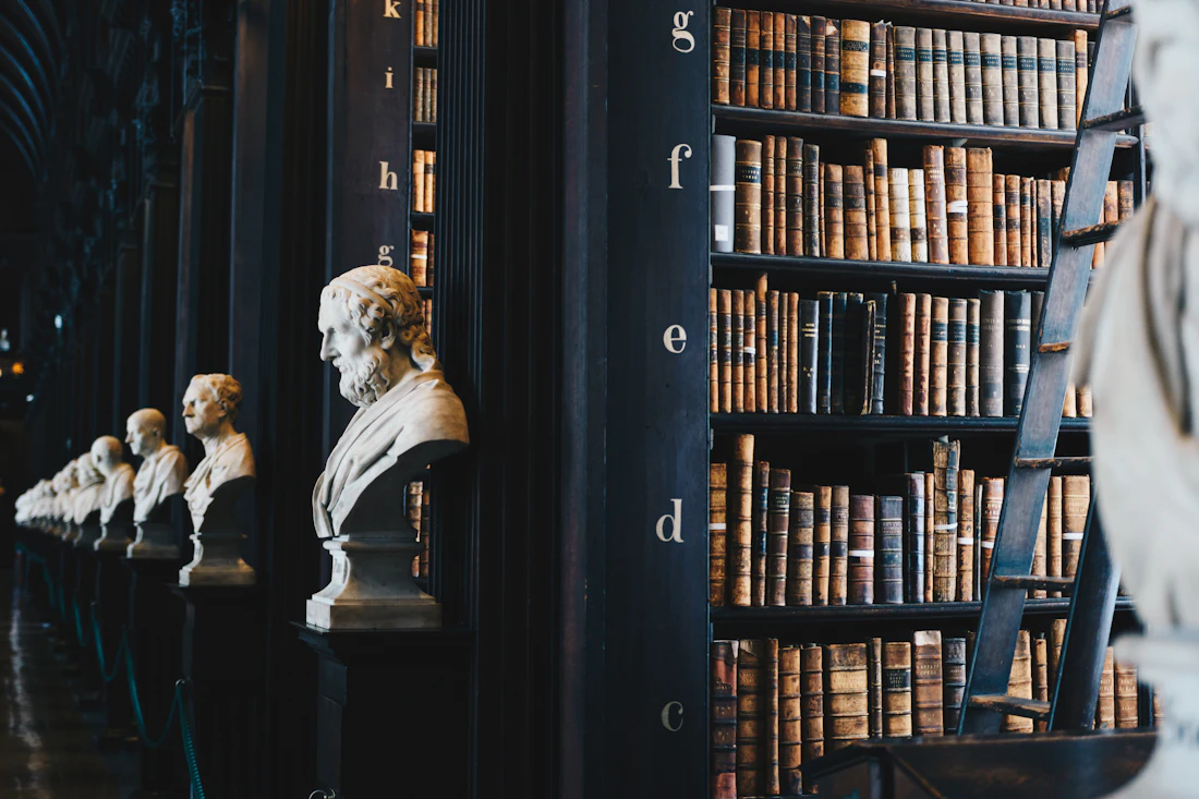 A long library hall lined with old bound volumes and marble busts.