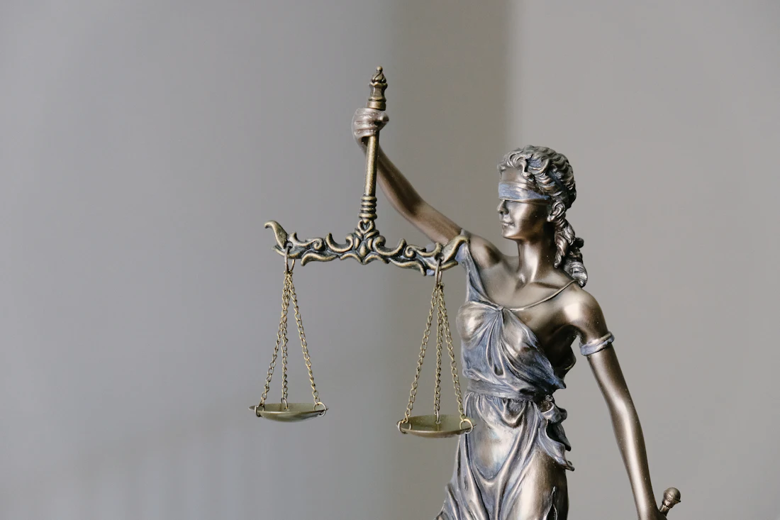 A cast figure of Justice, blindfolded, holding a set of balance scales.